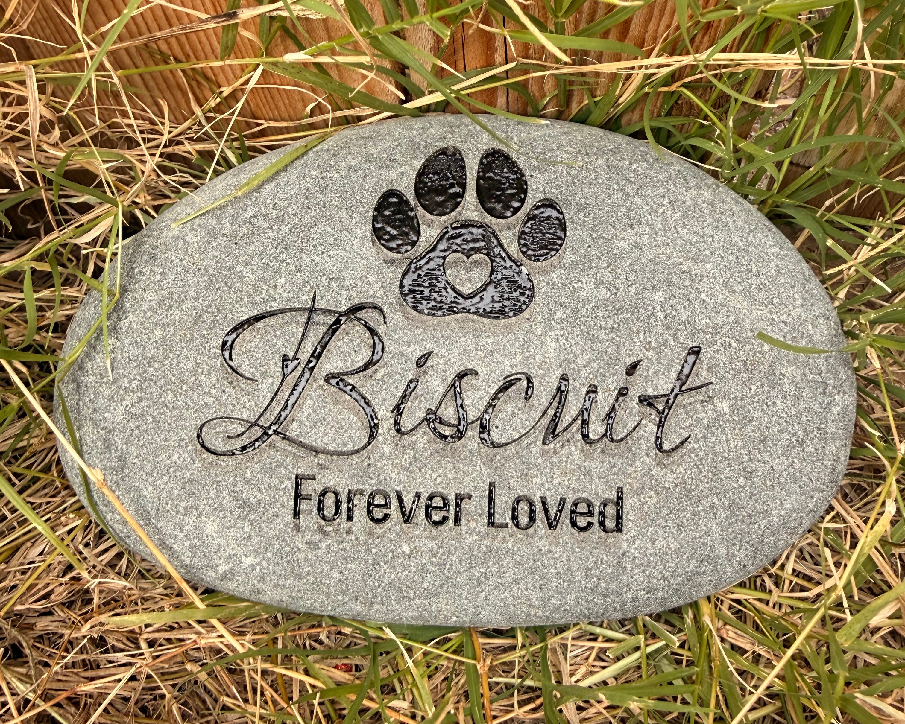 Decorative engraved stone with paw shape with heart in the middle over pet's name in decorative script and a memorial saying of "Forever Loved" underneath the name