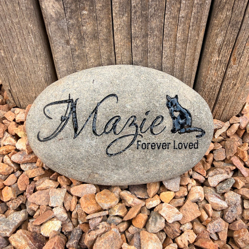 Decorative stone with engraved text on a wooden surface and gravel background